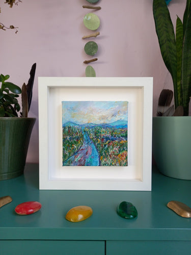 A framed painting of a mountain road fields and mountains Irish landscape
